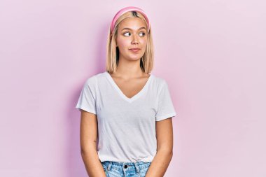 Güzel sarışın kadın, günlük beyaz tişört giyiyor gülümsüyor, yan tarafa bakıyor ve düşünüyor.. 