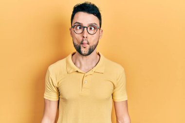 Günlük kıyafetler ve gözlük takan genç İspanyol adam dudaklarıyla balık suratı yapıyor, çılgınca ve komik bir jest. Komik ifade. 