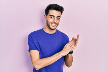 Gündelik tişört giyen genç İspanyol adam alkışlıyor ve alkışlıyor mutlu ve neşeli, gururlu eller bir arada. 