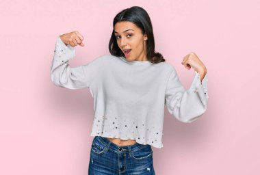 Sıradan kıyafetler giyen genç İspanyol kız gururla gülümseyen kol kaslarını gösteriyor. fitness konsepti. 