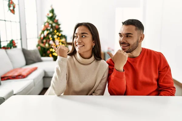 Junges Hispanisches Paar Sitzt Auf Dem Tisch Weihnachtsbaum Lächelt Mit — Stockfoto