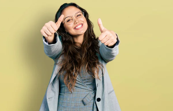 ビジネス服や眼鏡を身に着けている若いヒスパニック系の女の子は 手で積極的なジェスチャーを行うことを承認します 親指アップ笑顔と成功のために幸せ 勝者のジェスチャー — ストック写真