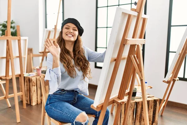 若いヒスパニックアーティスト女性絵画上のキャンバスでアートスタジオ放浪挨拶幸せと笑顔 優しい歓迎ジェスチャー — ストック写真