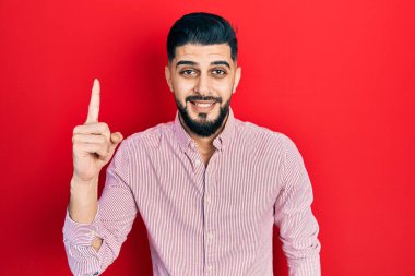 Kırmızı gömlekli, sakallı yakışıklı adam başarılı bir fikri işaret ediyor. Heyecanlı ve mutlu. Bir numara.. 