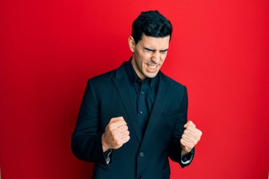 İş elbiseleri giyen yakışıklı İspanyol. Başarı için heyecanlanan kolları havada ve gözleri kapalı zaferi kutlarken gülümseyen. Kazanan konsept. 