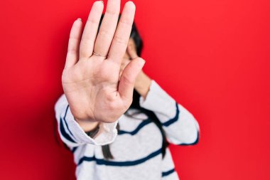 Latin kökenli genç bir kız, günlük kıyafetler giyip, elleriyle gözlerini kapatıyor ve üzgün ve korku ifadeleriyle dur hareketi yapıyor. utangaç ve olumsuz kavram. 