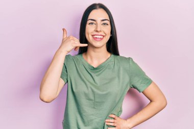 Mavi gözlü, sıradan tişörtlü, gülümseyen, el ve parmaklarıyla telefonla konuşan güzel bir kadın. iletişim kavramları. 