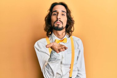 Genç, İspanyol asıllı, şık giyinmiş bir adam kameraya bakıyor ve havada bir öpücük savuruyor. Sevimli ve seksi. aşk ifadesi. 