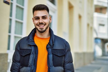 Yakışıklı, sakallı, neşeli ve kendine güvenen, kışlık palto giyen bir İspanyol.