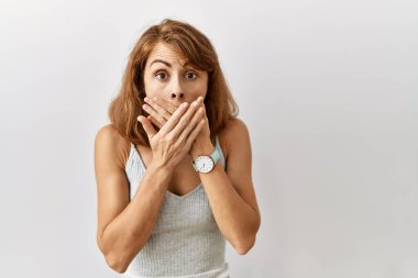 Güzel, beyaz bir kadın izole edilmiş arka planda dikiliyor. Ağzını yanlışlıkla ellerle kapatıyor. gizli kavram. 