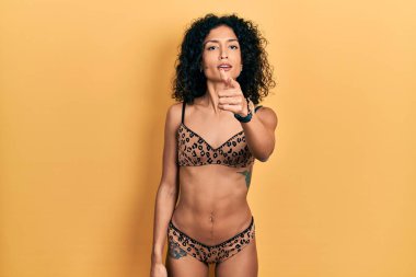 Genç Latin kız bikini giyip kameraya kızgın ve sinirli bir şekilde seni işaret ediyor. 