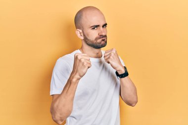 Genç kel adam, günlük beyaz t-shirt giyiyordu. Yumruk savunma hareketiyle dövüşmeye hazırdı. Kızgın ve üzgün bir yüz, sorundan korkuyordu. 