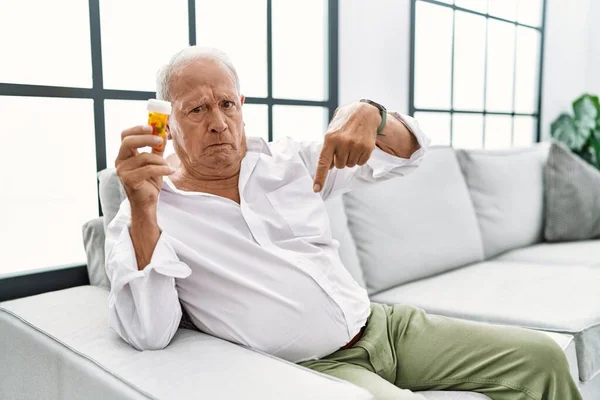 Senior Man Håller Piller Pekar Ner Ser Ledsen Och Upprörd — Stockfoto