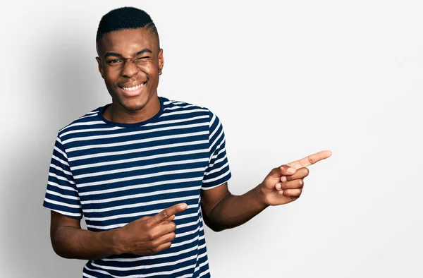 Jovem Afro Americano Apontando Com Dedos Para Lado Piscando Olhando — Fotografia de Stock