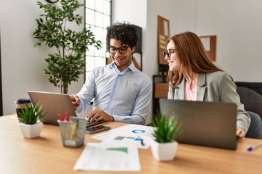 Ofiste dizüstü bilgisayarla çalışırken gülümseyen iki iş adamı..