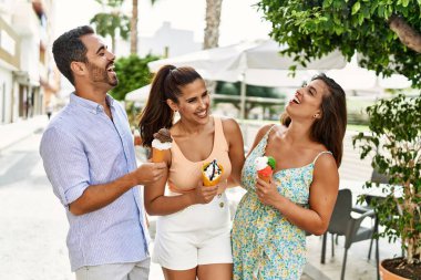 Üç İspanyol arkadaş gülerek şehirde dondurma yiyor..