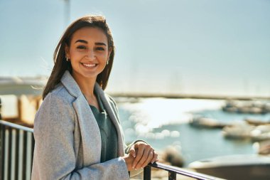 Genç İspanyol kız gülümsüyor mutlu bir şekilde kentteki korkuluklara yaslanıyor..