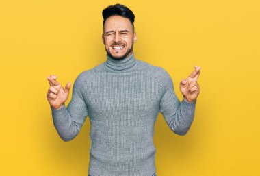 Gündelik giysiler giyen genç bir Arap umut ve gözlerin kapalı bir şekilde el işareti yaparak gülümsedi. Şans ve batıl inançlar. 