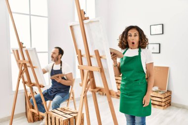 İspanyol orta yaşlı kadın ve sanat stüdyosundaki olgun adam şaşkınlık ve şaşkınlık içinde, ağzı açık ve korkmuş bir şekilde, inançsız bir yüz. 