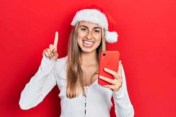 Mulher Hispânica Bonita Usando Chapéu Natal Segurando Smartphone Sorrindo Com — Fotografia de Stock