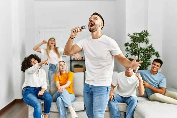 Bir grup genç arkadaş evde mikrofon kullanarak şarkı söylüyor..