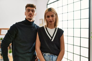 Ofiste, yüzünde ciddi bir ifadeyle iş kıyafeti giyen iki güzel iş adamı. Basit ve doğal bir şekilde kameraya bakıyorsun.. 