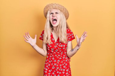 Sarışın, yaz şapkası takan, deli gibi bağıran, agresif ifade ve kollarıyla bağıran güzel beyaz bir kadın. hüsran kavramı. 