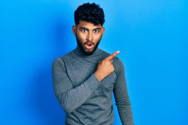 Balıkçı yaka kazak giyen sakallı bir Arap parmağını yana çevirerek şaşırdı, ağzı açık hayret içinde kaldı.. 