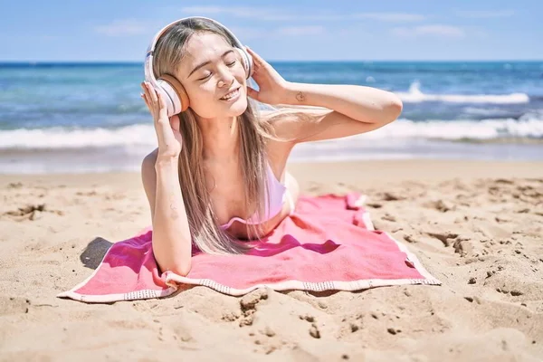 若いです中国の女の子身に着けていますビキニリスニング音楽にザビーチ — ストック写真