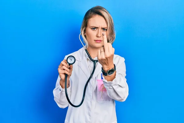 Beautiful Young Blonde Doctor Woman Holding Stethoscope Showing Middle Finger — Stock fotografie