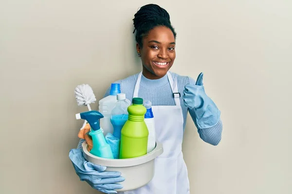 Mujer Afroamericana Con Cabello Trenzado Usando Delantal Sosteniendo Productos Limpieza —  Fotos de Stock