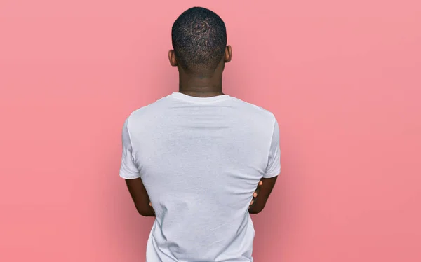 年轻的非洲裔美国人 身穿宽松的白色T恤 背向后站着 交叉双臂向外看去 — 图库照片