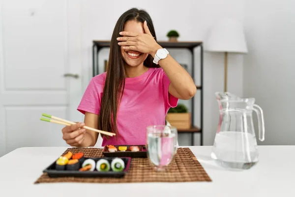 年轻的黑发女人在吃寿司时 用筷子笑着 用手捂住眼睛笑着表示惊讶 盲目概念 — 图库照片