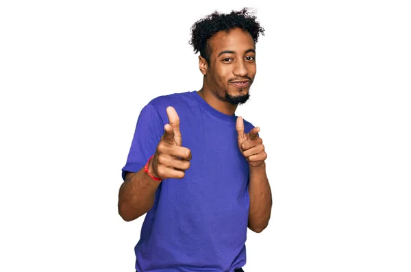 ひげを生やした若いアフリカ系アメリカ人の男性は 幸せと面白い顔をしたカメラに指を指してカジュアルな紫色のTシャツを着ていた 良いエネルギーと振動は — ストック写真