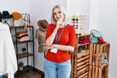 Perakende mağazasında yönetici olarak çalışan beyaz bir kadın kameraya kollarını kavuşturup gülümseyen ve çenesini kaldırmış bir şekilde bakıyor. Olumlu düşünmek. 