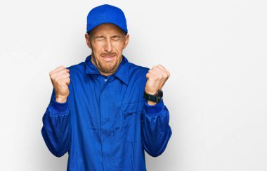 Kel, sakallı, inşaatçı kıyafeti giyen, başarılı olacağı için heyecanlanan, kolları havada, gözleri kapalı, zaferi kutlayan, gülümseyen bir adam. Kazanan konsept. 