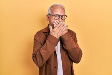 Gri saçlı, günlük ceket giyen ve gözlük takan son sınıf öğrencisi yanlışlıkla ağzı ellerle kapatmış. gizli kavram. 