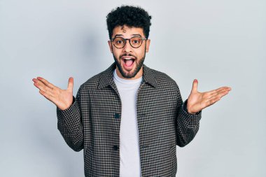 Sakallı genç Arap adam çılgın kutlama gözlüğü takıyor ve başarıyı kolları açık ve gözleri açık heyecanla haykırarak kutluyor. Kazanan konsept 