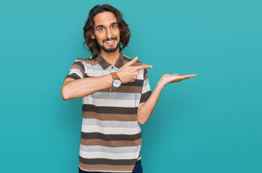 Gündelik kıyafetler giyen genç İspanyol adam kameraya hayret ediyor ve gülümsüyor.. 