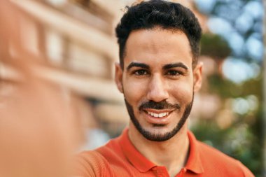 Genç İspanyol gülümseyen adam şehirde fotoğraf çekerken mutlu oluyor..