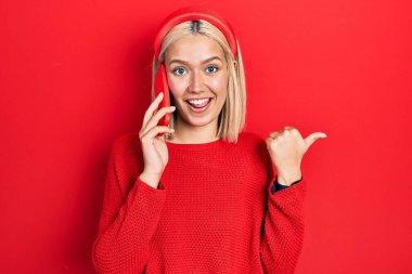 Güzel sarışın kadın akıllı telefondan konuşuyor. Parmağını kaldırıyor, gülümsüyor, ağzı açık. 