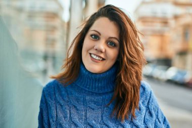 Genç İrlandalı artı cüsseli kız gülümseyerek şehirde mutlu mesut duruyor..