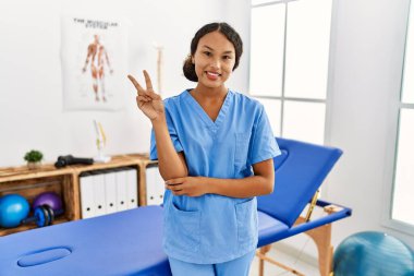 Ağrı kesici kliniğindeki güzel İspanyol fizyoterapist kadın kameraya bakıp gülümsüyor ve zafer işareti yapıyor. İki numara.. 
