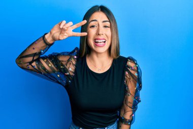 Genç İspanyol kadın zafer jesti parmakları gözlerinde gülümseme ve kahkahalarla gülme çünkü komik çılgın bir şaka.. 