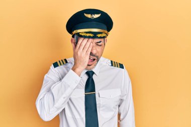 Yakışıklı, orta yaşlı, gri saçlı, uçak pilotu üniforması giyen, yarı yüzü, gözü ve ağzı kapalı, yorgun bir adam. Yüzüm acıyor.. 