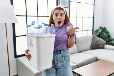 Elinde plastik şişelerle çöpleri geri dönüşüm sepetini tutan genç, kızıl saçlı bir kadın el ile yüzünü göstererek şaşırdı, ağzı açık hayret içinde kaldı.. 