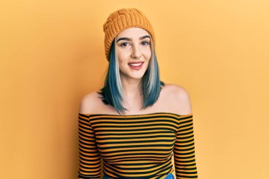 Yüzünde mutlu ve havalı bir gülümseme olan yün şapka giyen genç modern bir kız. şanslı kişi. 