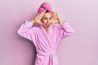 Duş havlusu şapkası ve bornoz takan neşeli bir şekilde gülümseyen genç sarışın kadın elleriyle bir böceği dikizliyor. Şaşırdım ve çıktım. 