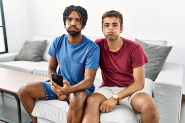 Genç ispanyol adamlar akıllı telefon kullanıyor evde kanepede oturmuş komik suratlarıyla yanaklarını şişiriyorlar. Havayla şişmiş ağız, çılgın bir ifade.. 