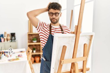 Sanat stüdyosundaki Arap genç adamın kafası karışıyor ve merak ediyor. Şüpheyle kararsız, kafa kafaya düşünerek. Düşünceli kavram. 